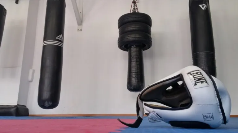 Sacchi da boxe appesi e un casco da combattimento sul tatami